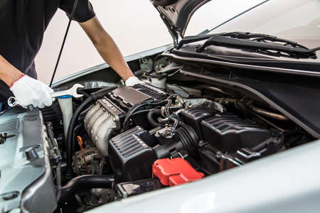 Close-up hands of auto mechanic are using the wrench to repair and maintenance auto engine is problems at car repair shop. Concepts of car care check and fixed and services insurance.の写真素材