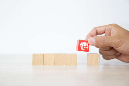 Close-up hand choose cube wooden toy blocks stack with franchise business store icon for business growth and  branch expansion strategy of financial marketing planning concepts.の写真素材