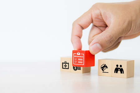 Close-up hand chooses cube wooden toy blocks stacked with insurance prevent and protect icon for safety family health insurance and car accidents prevention and shield concepts.の写真素材