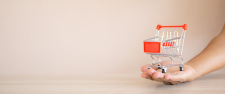 The shopping cart on hand of businessman at desk. Concept of using the applicationの写真素材