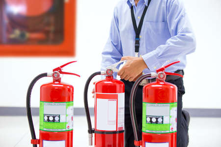Firefighter checking the handle of the red fire extinguishers tank in the building concepts of prevent case for emergency and safety rescue and fire training.の写真素材
