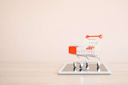 Close up the shopping cart on smartphone or tablet at desk concept using the internet application for online shopping buying and spending on computer technology.の写真素材