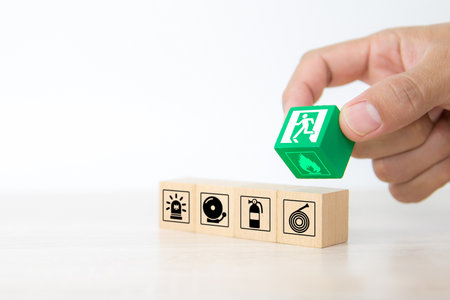 Close-up hand choose wooden toy blocks stacked with door exit sing or fire escape icon with fire extinguisher and emergency protection symbol for safety prevent and rescue.の写真素材