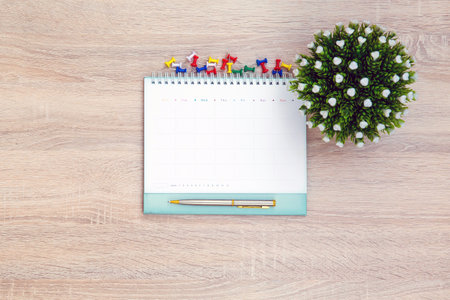 The top view desk and blank calendar with a pen and office equipment for working area copy space composition and work from home concepts.の写真素材