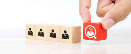 Hand choosing people icon with head light bulb on cube wooden toy block stacked. Concepts of human resources personnel selection and person organization job fit and employees performance.の写真素材
