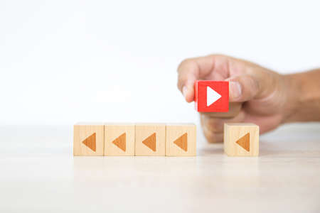 Close-up hand chooses arrow icon on cube wooden toy block stacked with pointing to opposite directions for way of adapting to change leader and transform concept.の写真素材