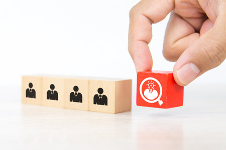 Hand choosing people icon with head light bulb on cube wooden toy block stacked. Concepts of human resources personnel selection and person organization job fit and employees performance.の写真素材