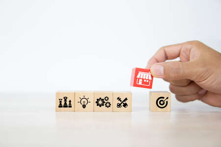Hand choose cube wooden toy blocks stacked with franchise business store icon for growth and strategy of financial marketing planning and bank loan for branch expansion franchisee.の写真素材