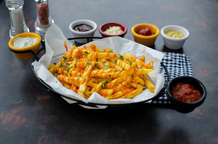 Basket of French Fries and chicken with sauces on dark background. Top view