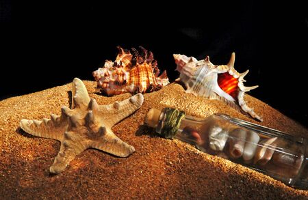 Sea shells and stones in a bottle on sea-beach background. Photograph is made in lightbrush...