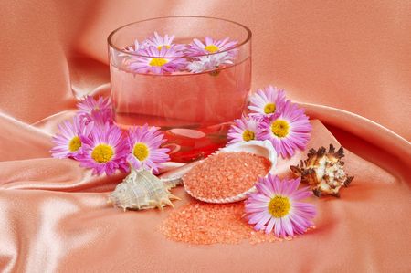 A bright pink spa and body care background. Salt and flower floating in glass bowl.の写真素材