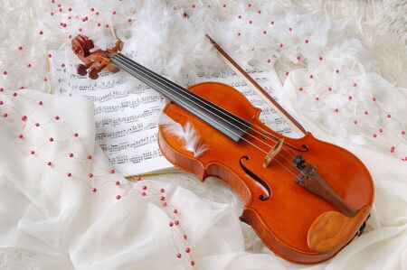 Violin and notes on white silk background with boa and furs