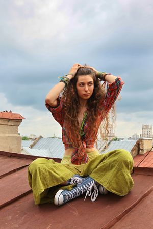 Young girl sitting on a iron roofの写真素材
