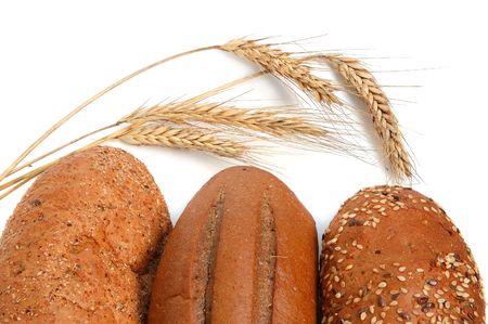 Homemade whole bread and shafts of wheat on a white background