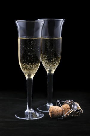 Pair of champagne flutes and cork on a black backgroundの写真素材