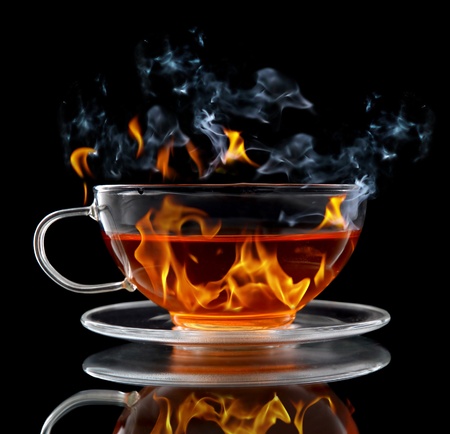 Class cup with burning hot tea on black backgroundの写真素材