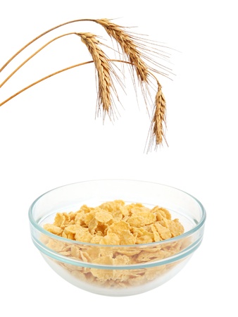 Bowl of cornflakes and wheat ears on white background
