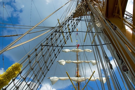 Sail and mast of old ship on a blue sky background