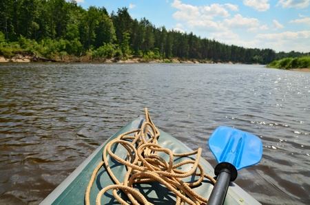 An inflatable kayak on the the Neman river in Belarus with wood landscape on background