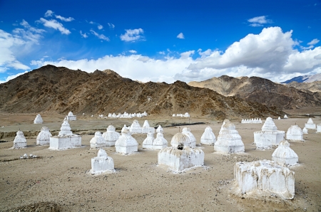 White buddhist chortens (stupas) and Himalayas mountains on the background in valley near Leh, Ladakh, Indiaの写真素材