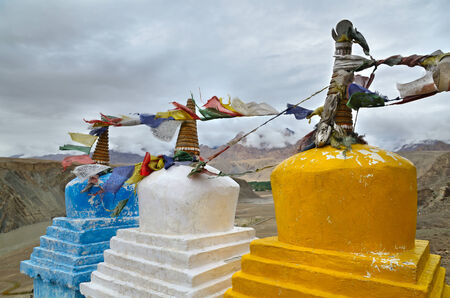 Buddhist chortens (stupas) with tibetan prayer flags near the confluence of the Indus and Zanskar rivers and Himalayas mountains , Ladakh, Indiaの写真素材