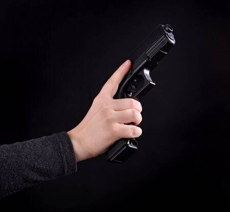 Close up of female hand with gun on a black background