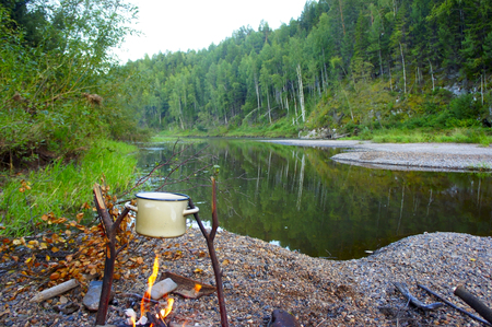 on the river bank with a fire cooking in the summerの写真素材