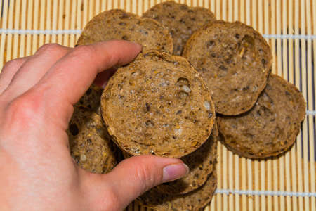 female hand holding a piece of rye bread wholemealの写真素材