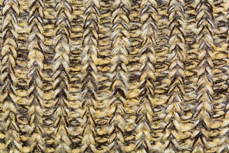 mottled texture of the wool yellow brown knitted fabric closeup