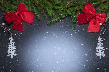 two white Christmas tree toys in the form of Christmas trees, two large red bows and branches of a...