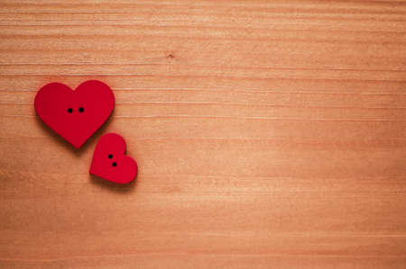 Two large and small red wooden hearts on a wooden surfaceの写真素材
