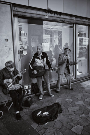 Three older men playing music in the center of Turin in Italy on May 8, 2022