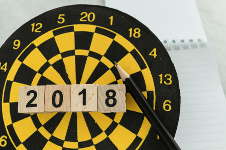New year planning target concept with wooden blocks number 2018 on dart board, pencil and note...