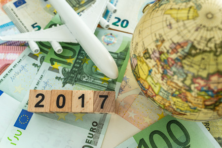 world europe travel concept as toy airplane and globe on pile of euro banknotes and number 2017 on...
