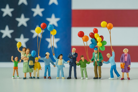 miniature people, happy american family holding balloon with United State national flag in the background as celebrating the Independence day.の写真素材