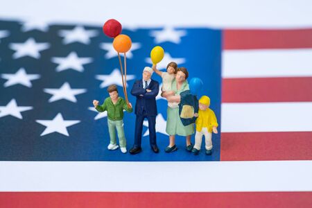miniature people, happy american family holding balloon with United State national flag in the background as celebrating the Independence day.の写真素材