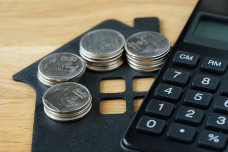 Soft focus on stack of coins on paper house with calculater as property or financial mortgage plan concept.の写真素材