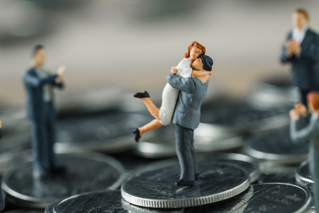 Miniature figure couple people standing on top stack of coins and other clapping as success love life concept.の写真素材