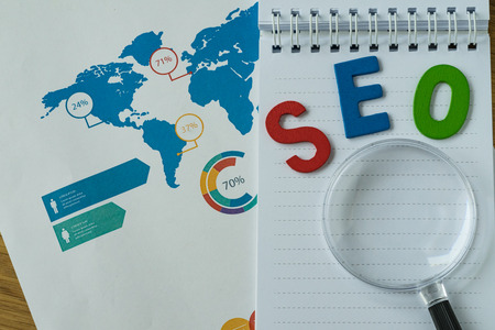 SEO concept as colorful alphabet abbreviation SEO on magnification glass on printed analysis chart and graph.の写真素材