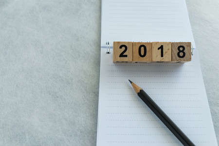 Next year goals or target concept with wooden blocks number 2018 and pencil on white note paper with copy space.の写真素材