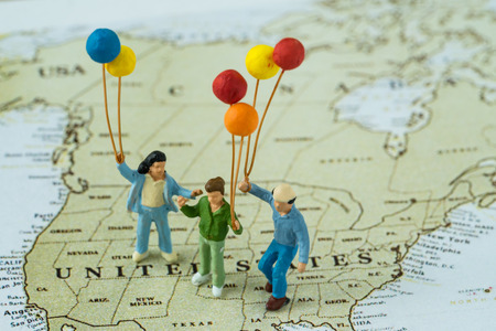 Miniature happy family holding balloons standing on United State map.の写真素材