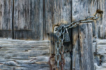 aged rusty chain with lock pad on old ancient wooden door.の写真素材