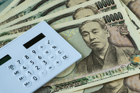 Calculator on pile of japanese yen banknotes as financial safe haven or tax concept.の写真素材