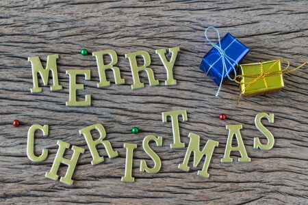 Golden alphabets Merry Christmas with colorful present box on wooden background as christmas celebration concept.の写真素材