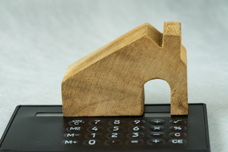 Selective focus on wooden miniature house on black calculator as property or financial mortgage plan concept.の写真素材