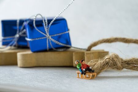 Miniature happy children riding the sleigh with the present box in the background as christmas eve...