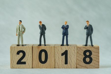 miniature businessmen standing on wooden block 2018 with white background as happy business new year concept.の写真素材