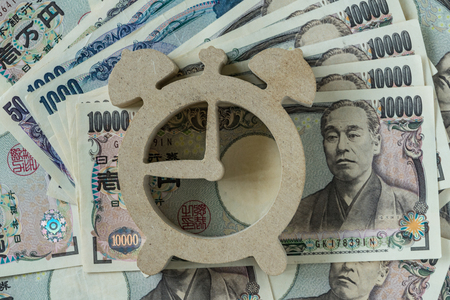 wooden alarm clock on pile of japanese yen banknotes as time count down or deadline financial concept.の写真素材