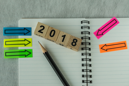 business target concept as selective focus on number 2018 wooden block with pencil, notebook, arrow stick paper.の写真素材