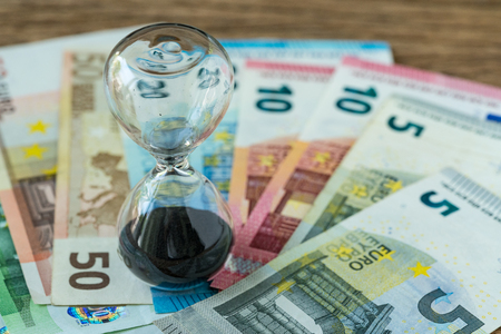 Business time countdown or long term investment concept as hourglass or sandglass on pile of Euro banknotes.の写真素材